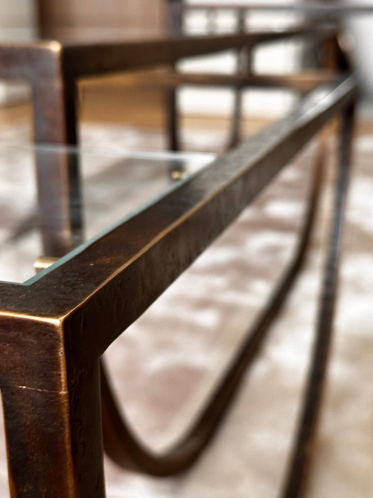 Asymmetrical metal-and-glass coffee table with curved architectural frame.