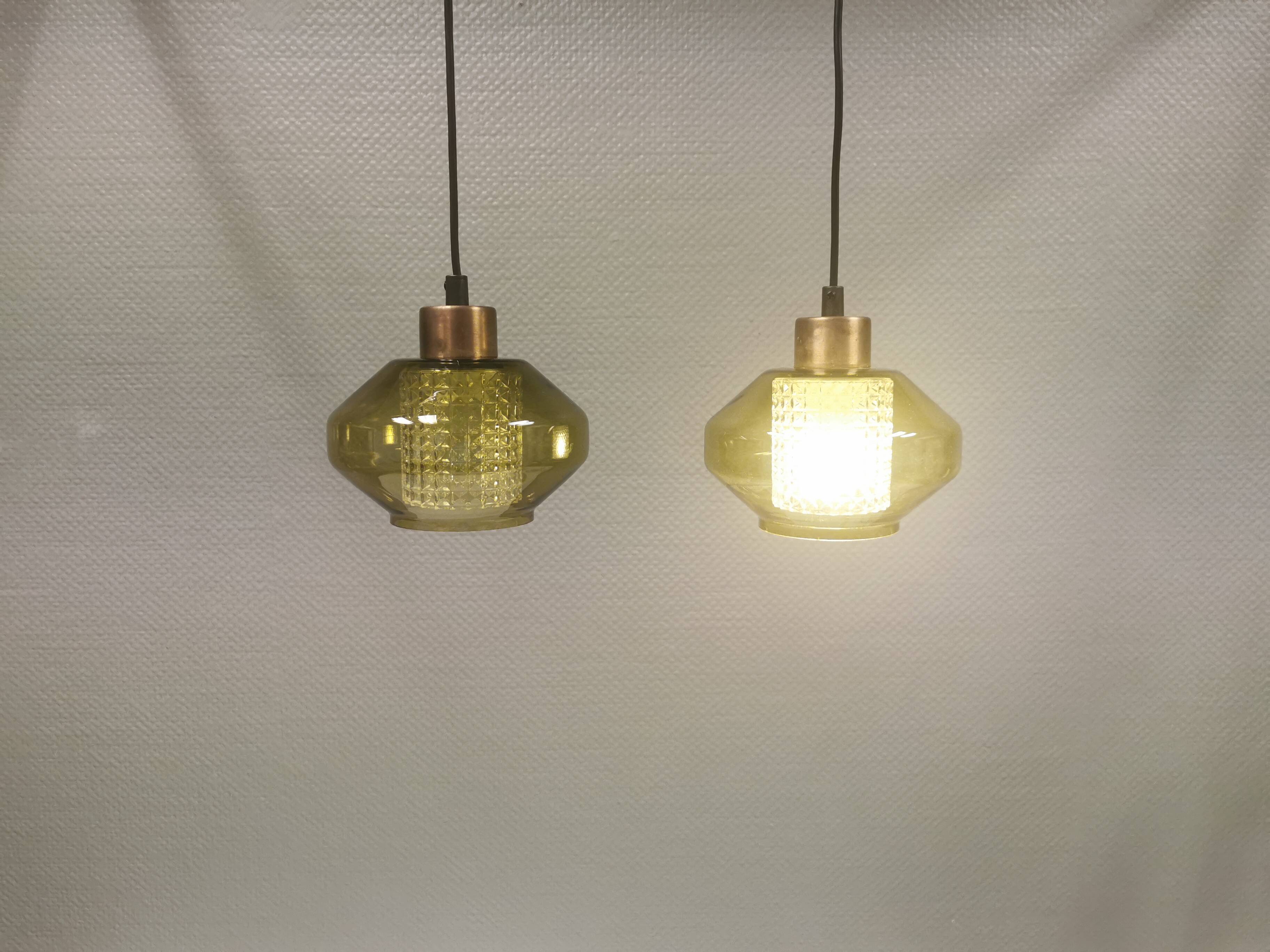 Hanging lamp with an outer shade of olive green glass and an inner shade of clear, crystal glass.