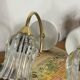Pair of wall sconces in brass with transparent tulip glass shade.