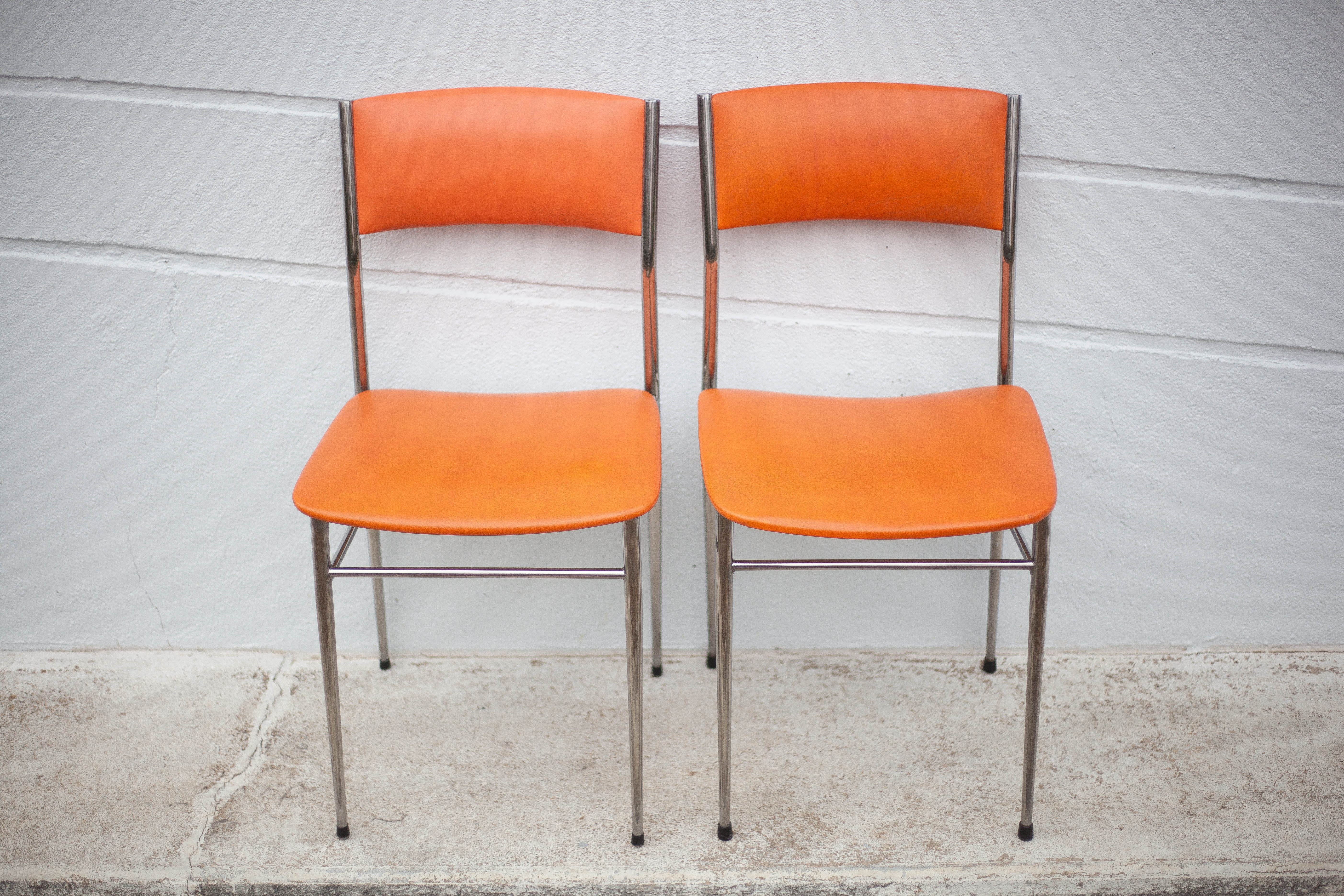 Pair of chrome metal chair and orange skai