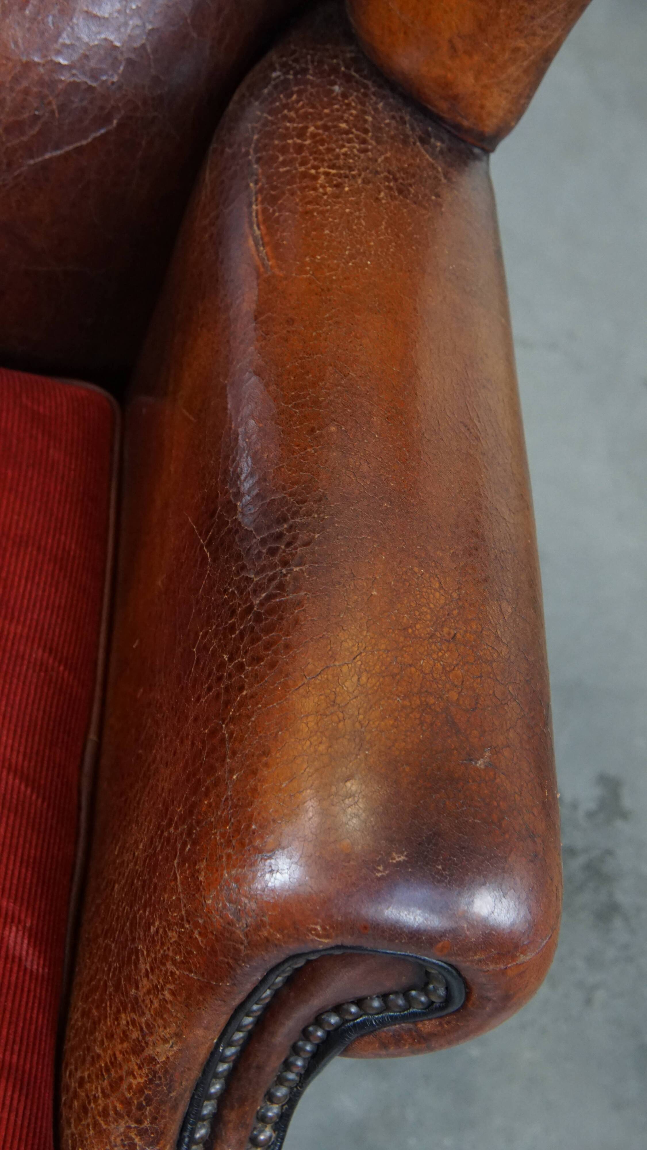Sheepskin leather wingback chair with a red corduroy seat cushion