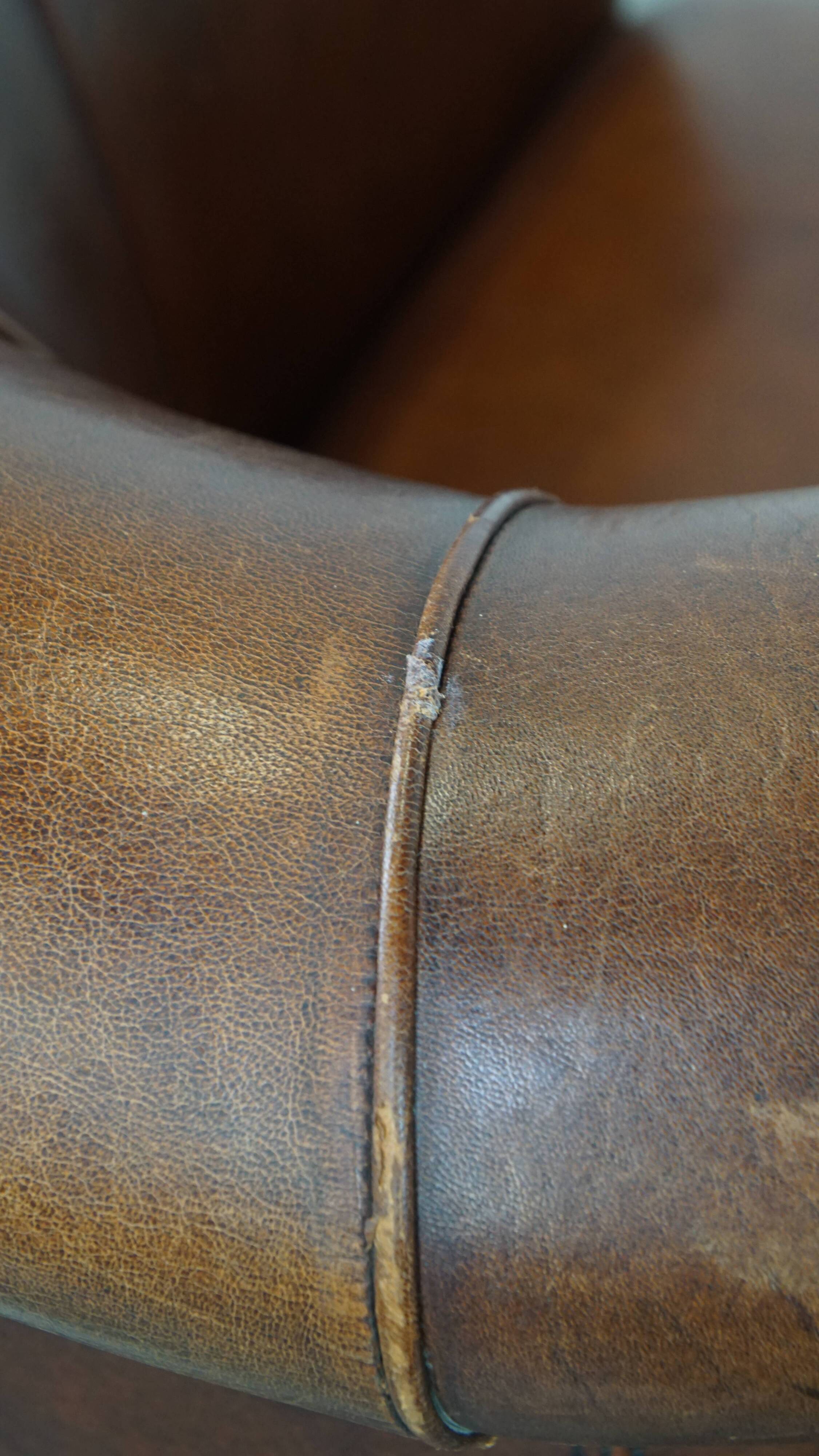 Sheep leather club chair in a cognac color and finished with piping