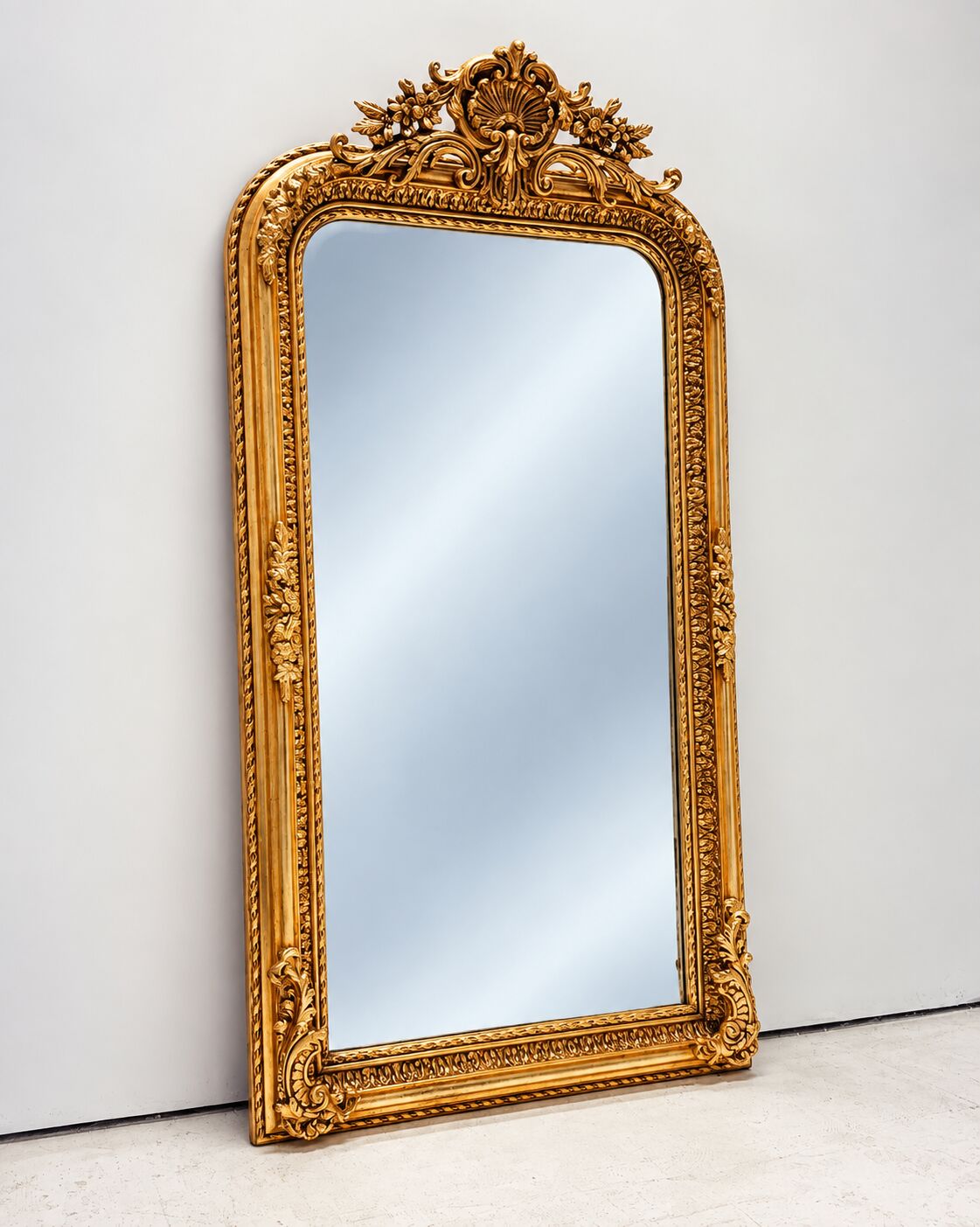 Grand miroir baroque en or avec un crête orné.