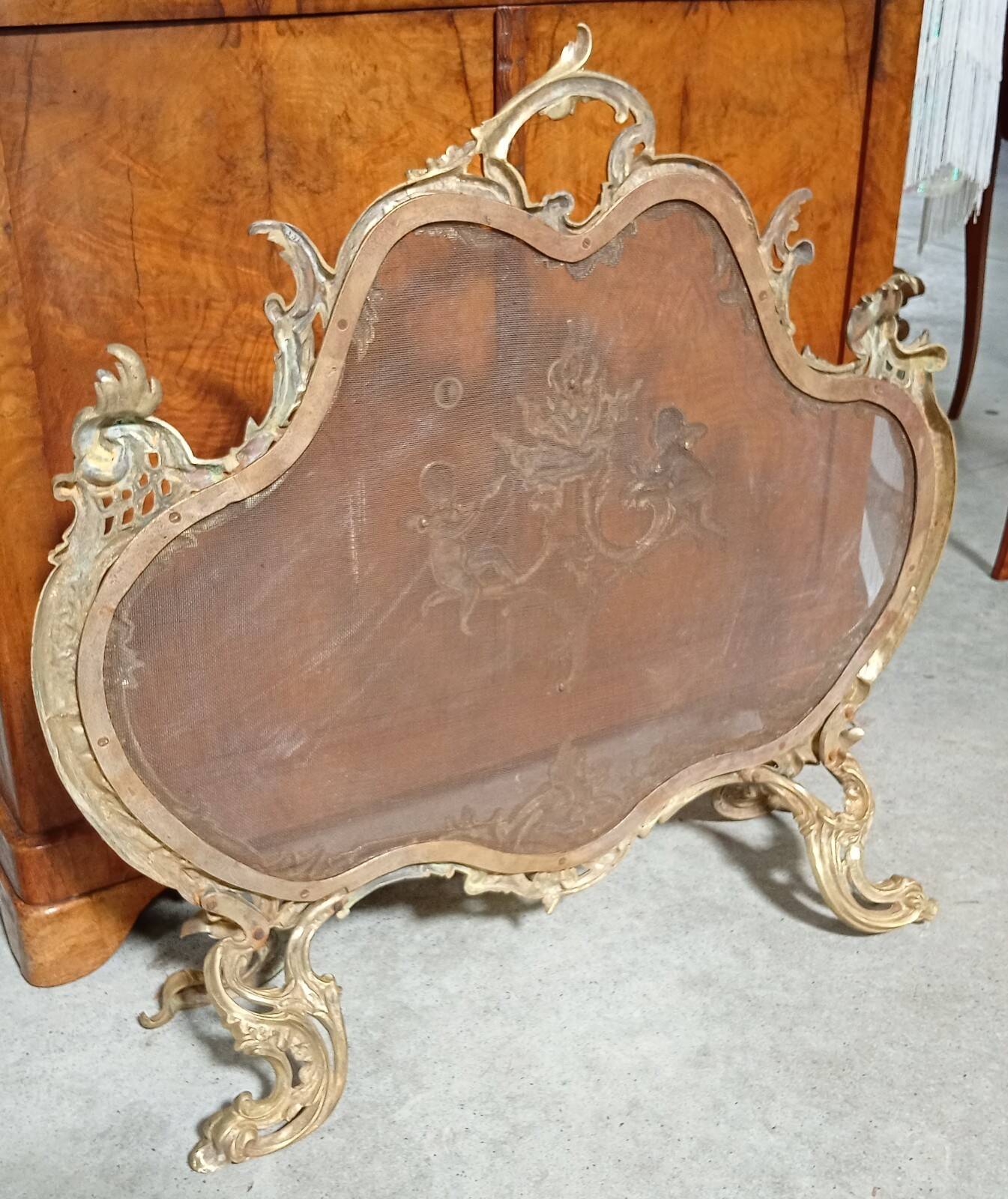 Large gilded bronze fireplace screen decorated with putti and rocaille motifs.