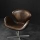 Brown leather Swan chair by Arne Jacobsen, mid-century Danish modernity.