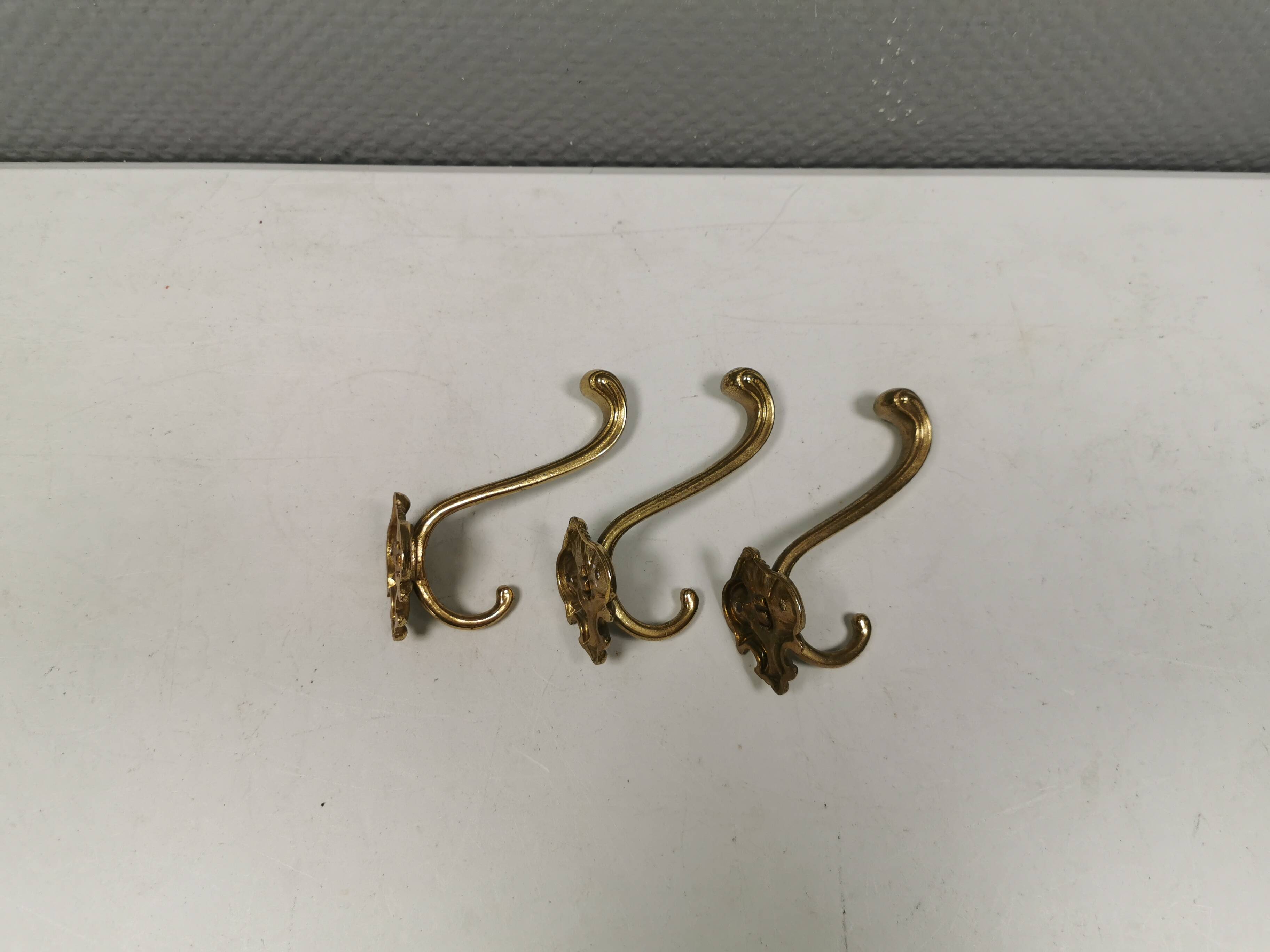 Three old and beautiful brass hooks with decorative motifs