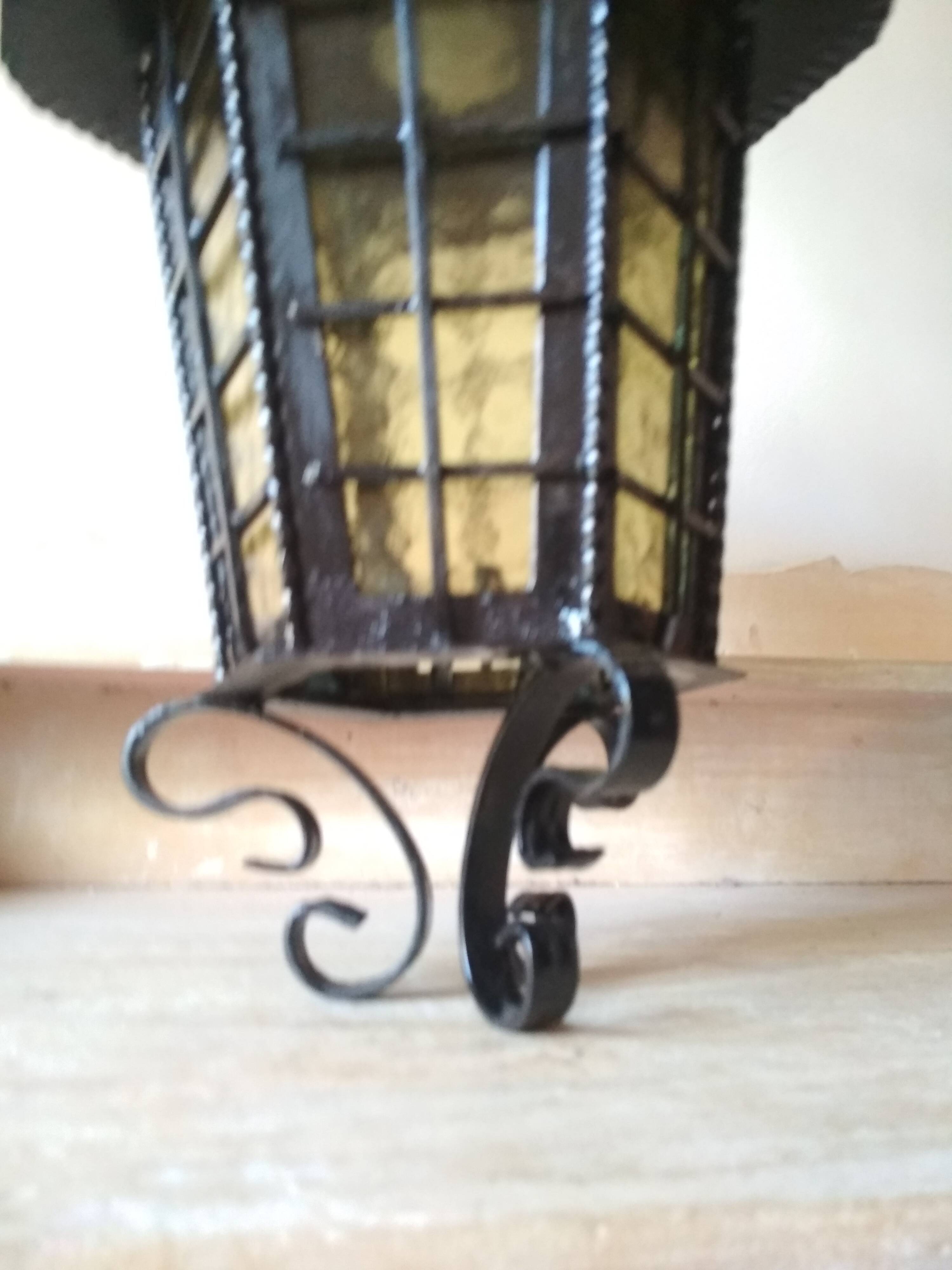 Large hanging lantern in wrought iron and opaque yellow-orange windows