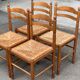 4 solid wood kitchen chairs with straw seats in a country farmhouse style.