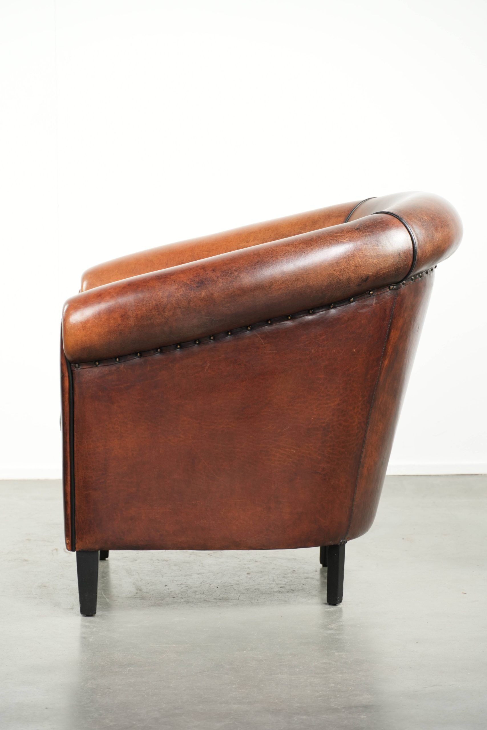 Sheepskin club armchair with deep warm colours and black piping