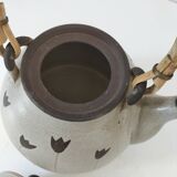 Beige stoneware teapot with stylized flowers and rattan handle