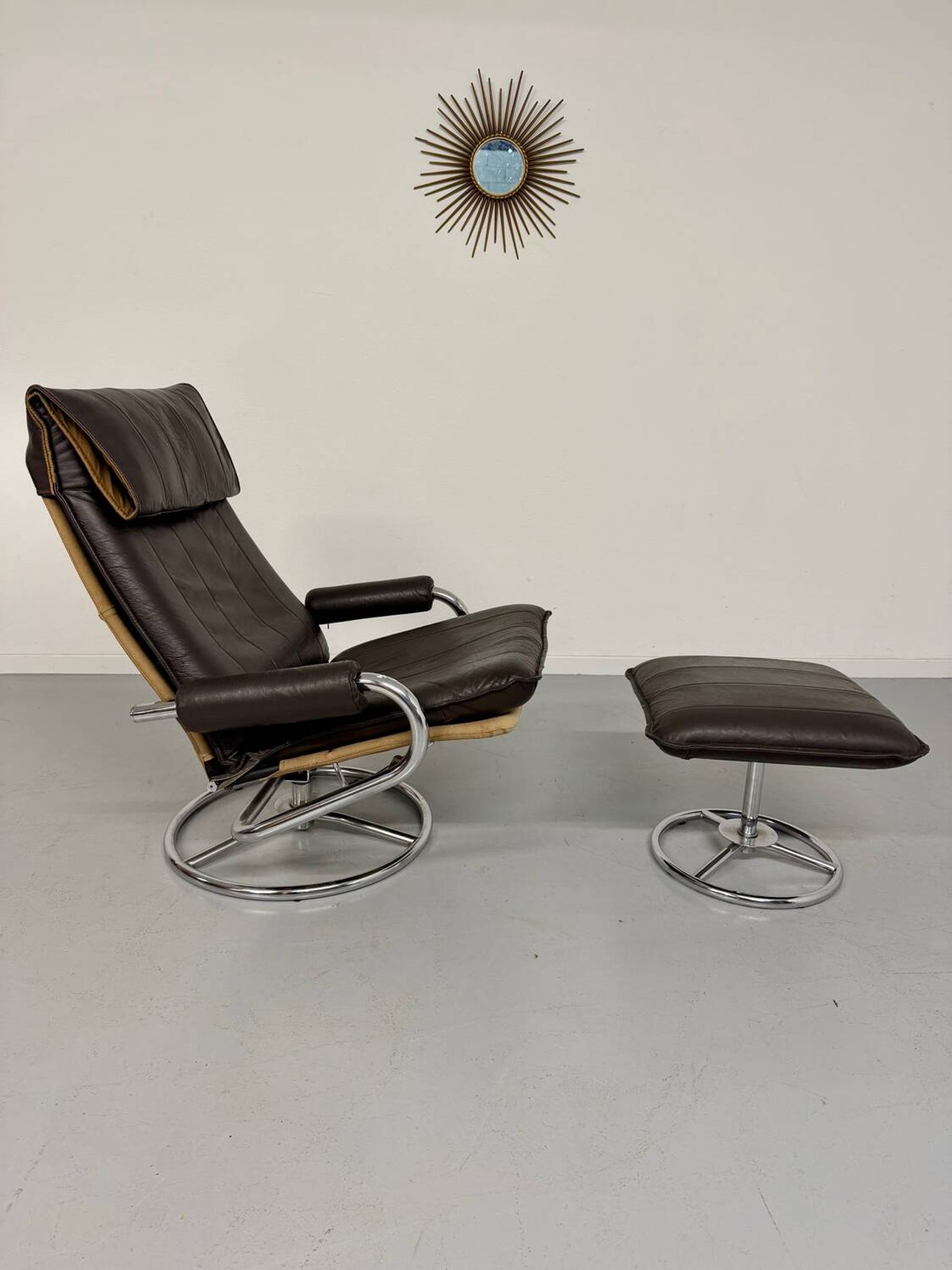 Vintage leather reclining armchair and its 1970s designer ottoman.
