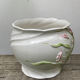 White ceramic pot cache of flower slip and old green foliage