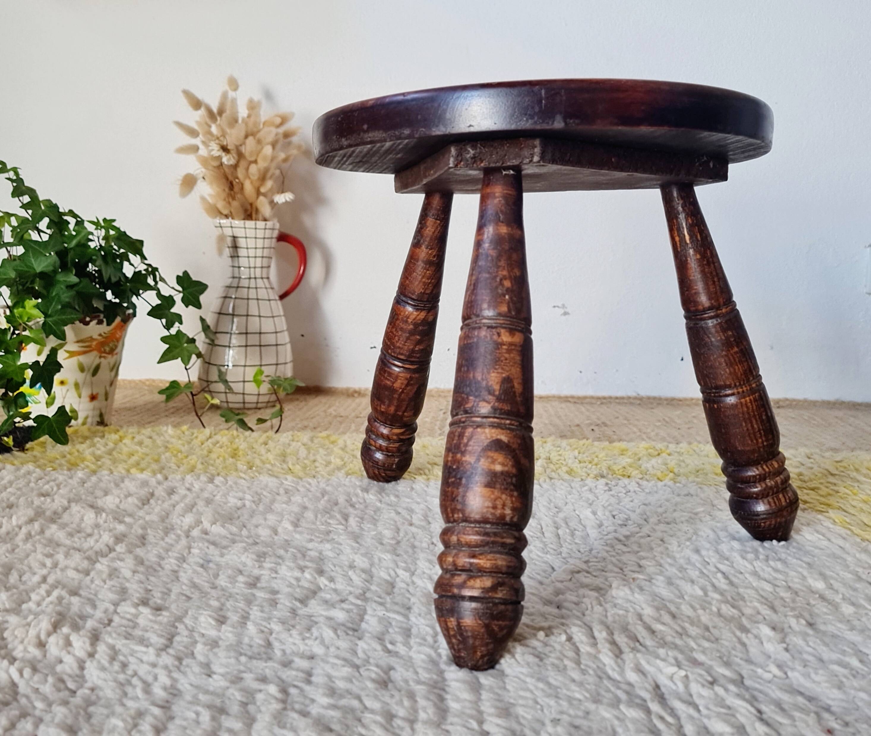 Small brutalist tripod stool made of turned wood.