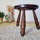 Small brutalist tripod stool made of turned wood.
