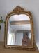 Miroir décoratif avec moulures et fronton.