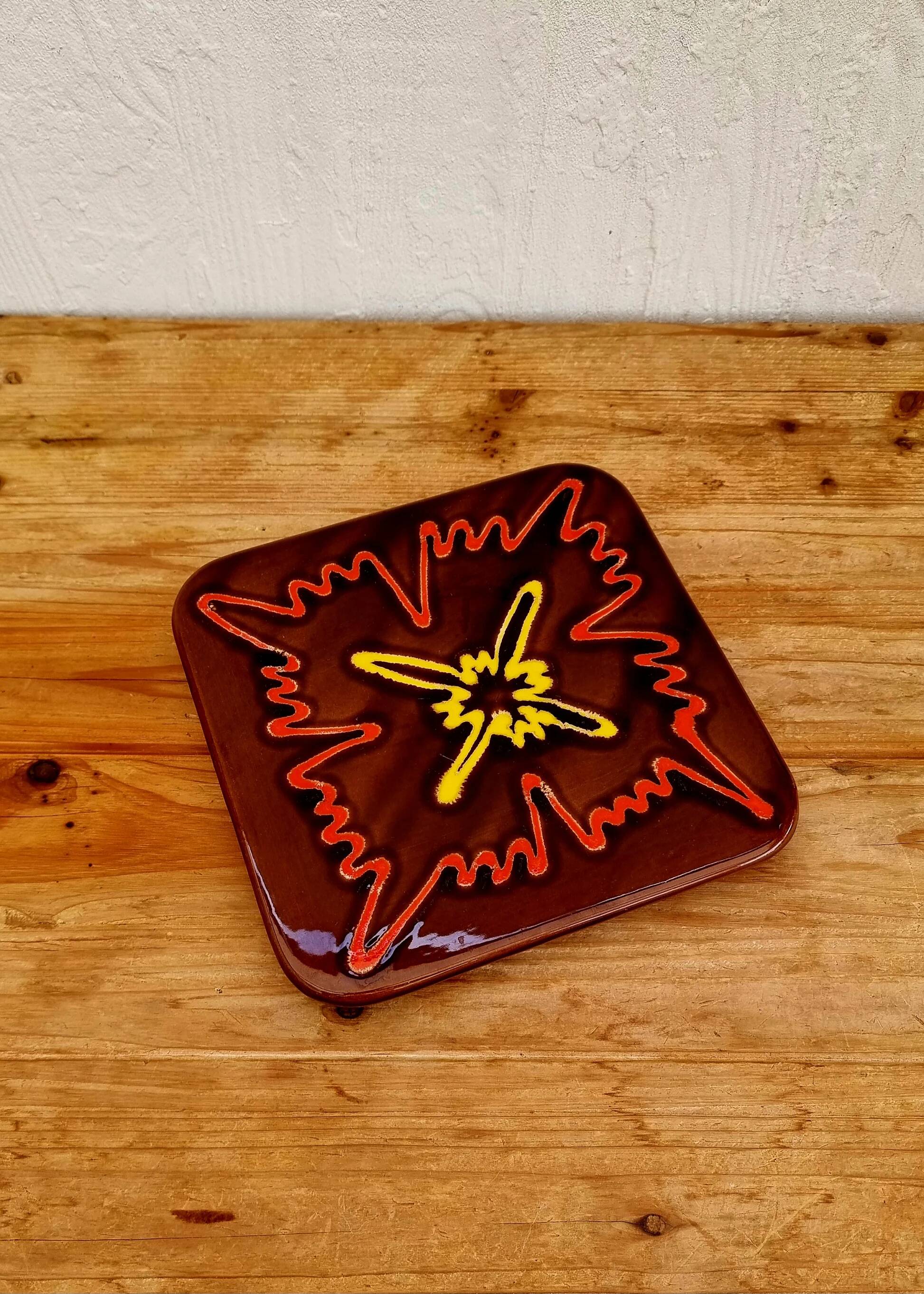 Vintage ceramic trivet with a 70s pattern.