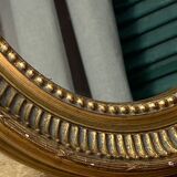 Oval-shaped wooden mirror in gold color