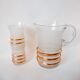 set composed of a pitcher and two large white granite glasses with gold edging from the 60s