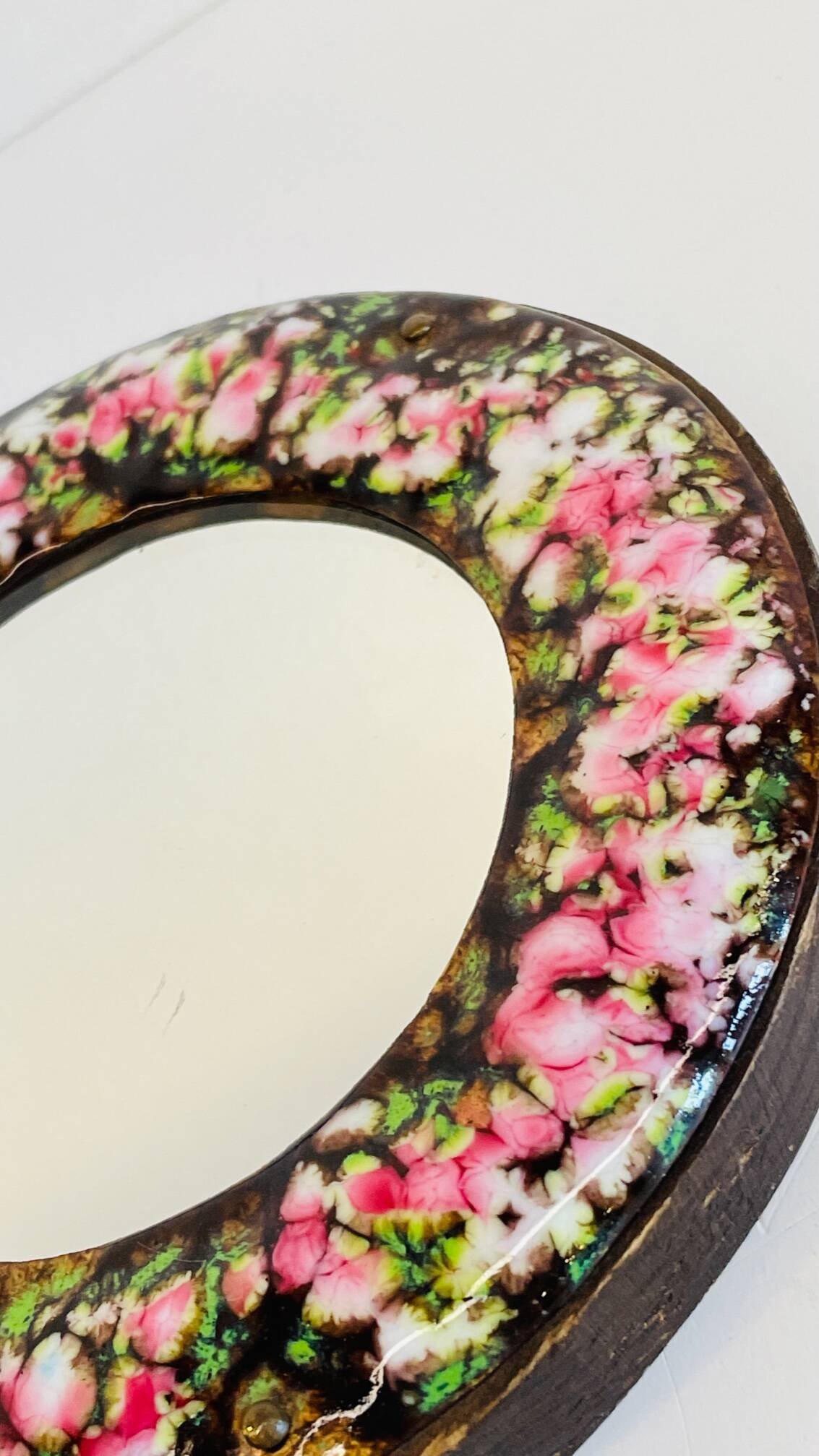 Vintage enameled metal hand mirror on wood