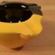 Two-tone ceramic ashtray in yellow and black, vintage 1950s.