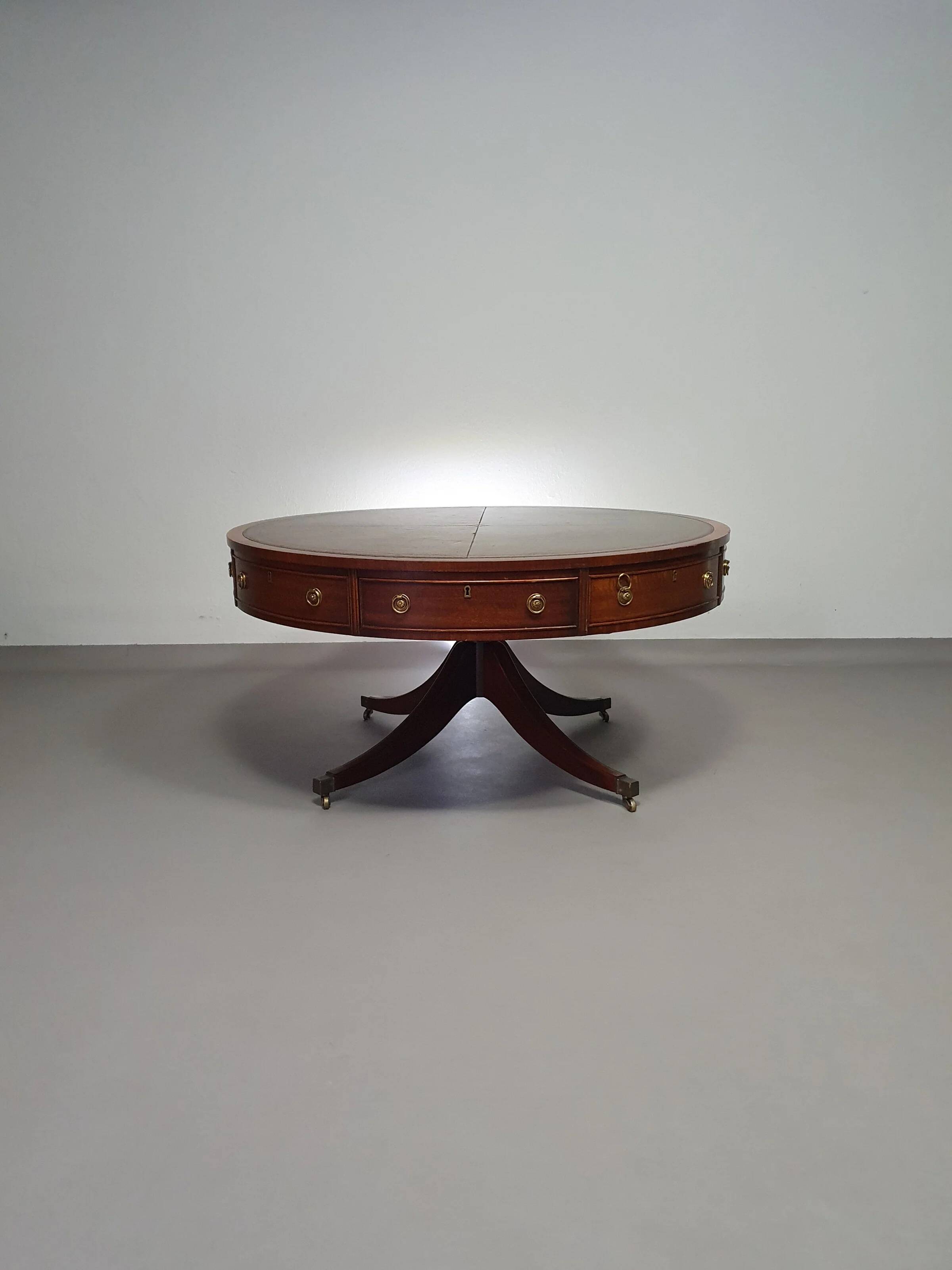 Table basse / table tambour victorienne « Heldense » en acajou avec plateau en cuir sur roulettes en laiton. Années 1980