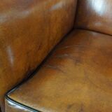 Art deco armchair in sheepskin with black piping and decorative nails