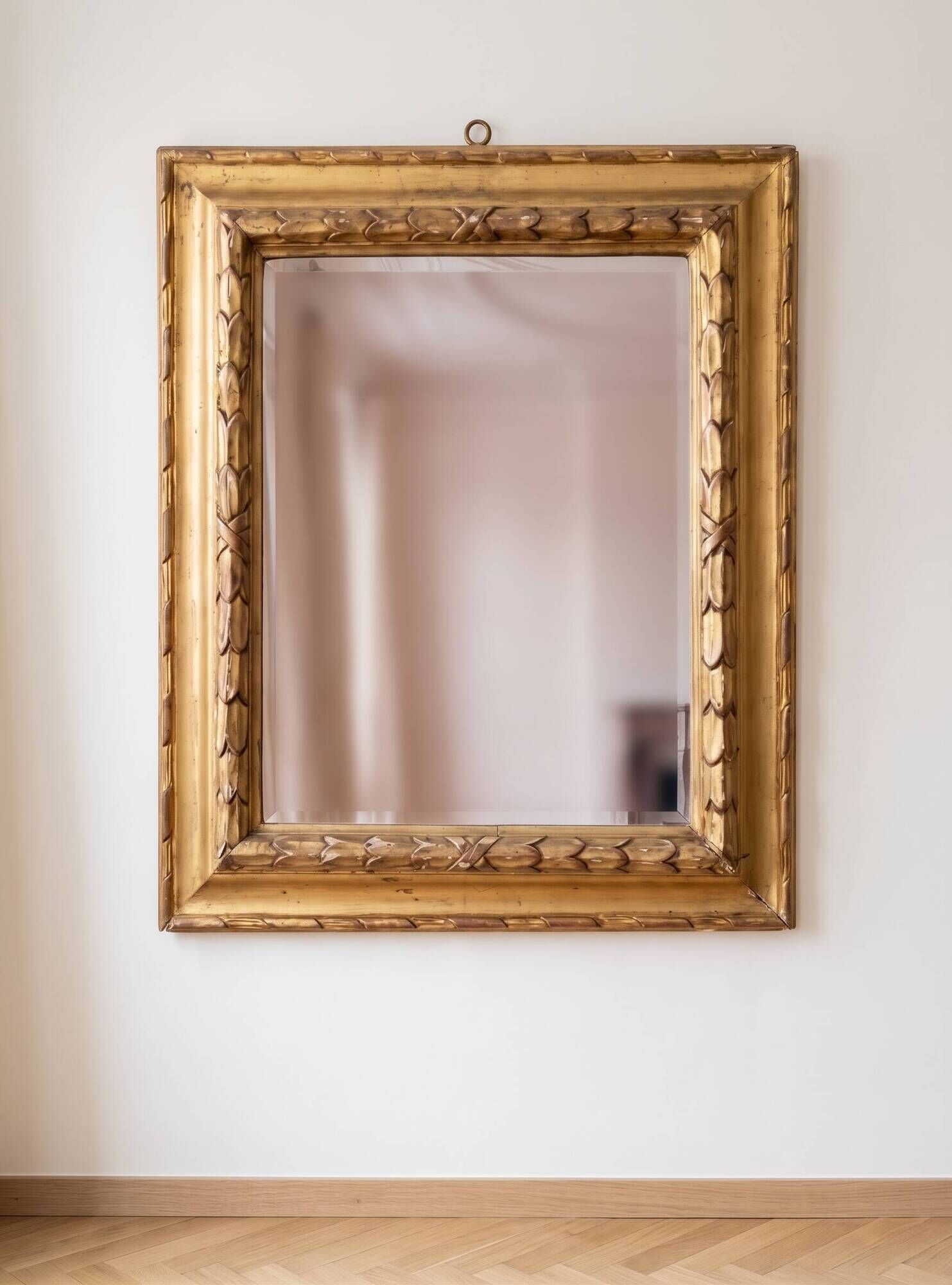 Antique wall mirror with a carved gilded frame featuring leaf motifs.