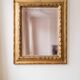 Antique wall mirror with a carved gilded frame featuring leaf motifs.