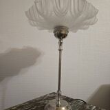 Table lamp with a silver base and a scalloped shade.