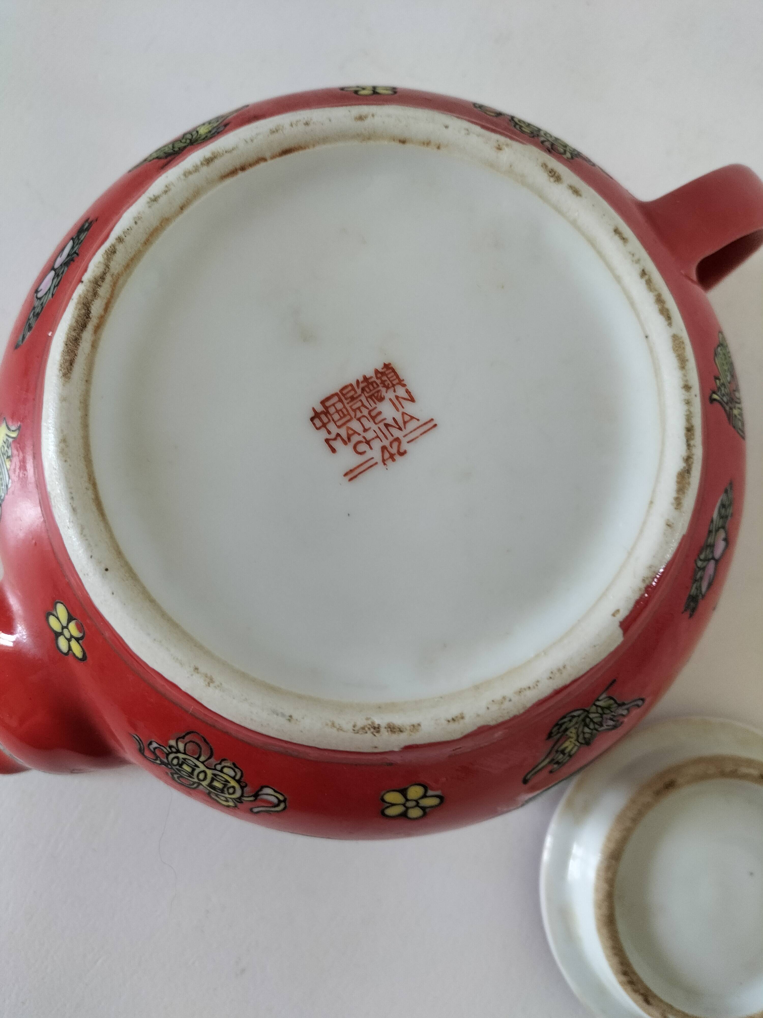 Vintage red Chinese teapot decorated with dragons and symbols.