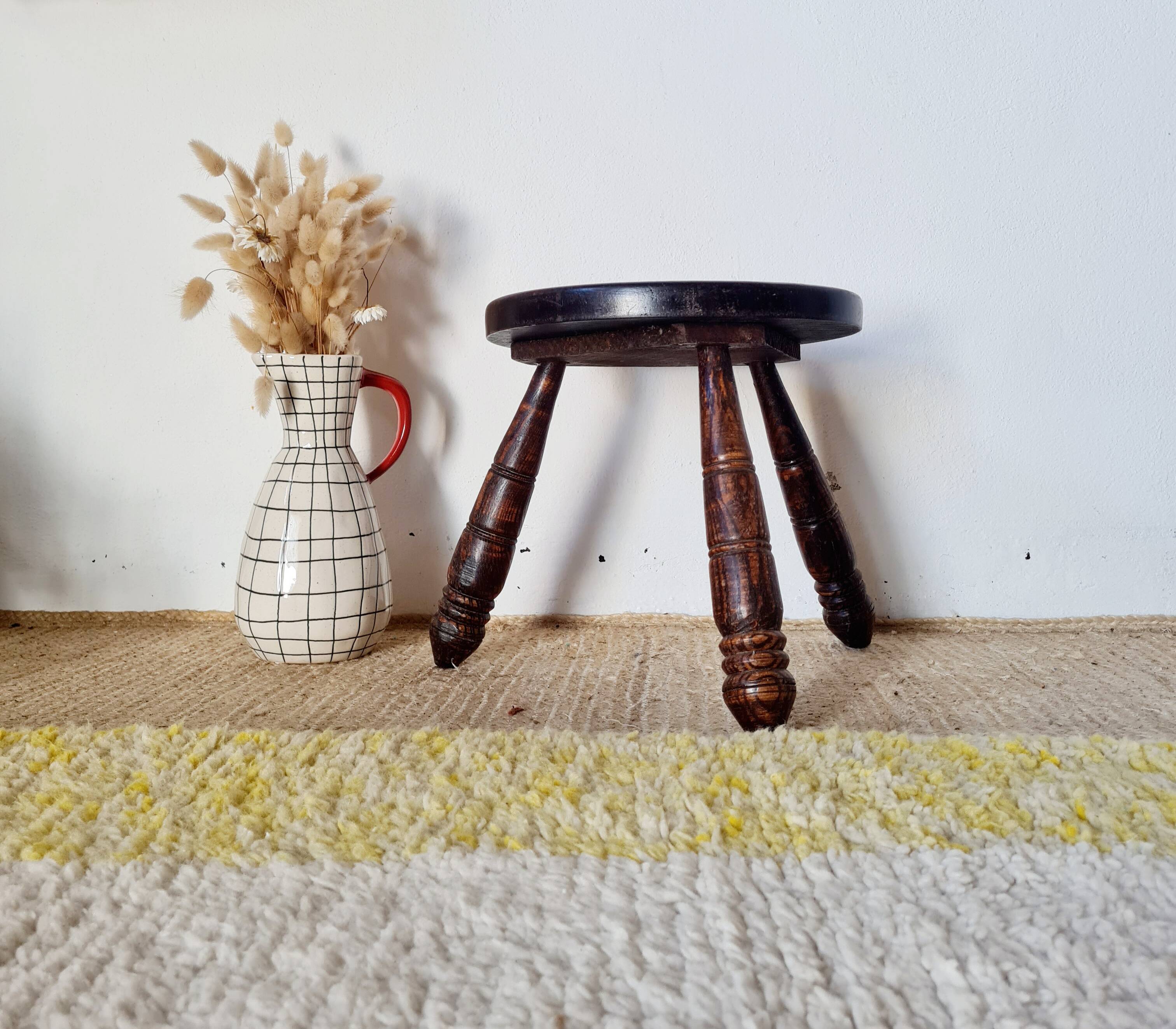 Small brutalist tripod stool made of turned wood.