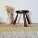 Small brutalist tripod stool made of turned wood.