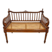 Hand-carved bench in Louis XVI style with woven cane seat.