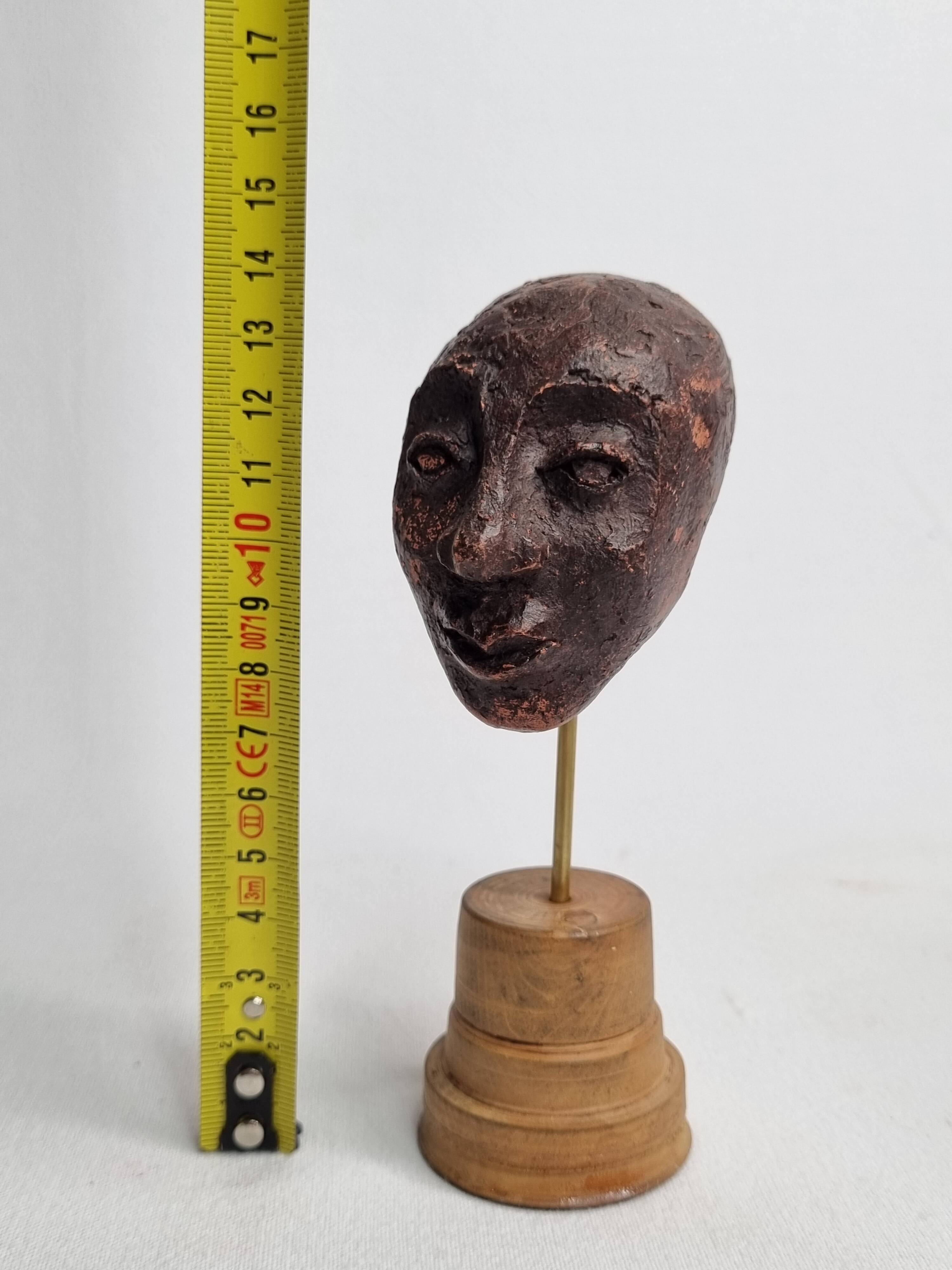 Expressive sculpted head in patinated terracotta on wooden base, 14 cm