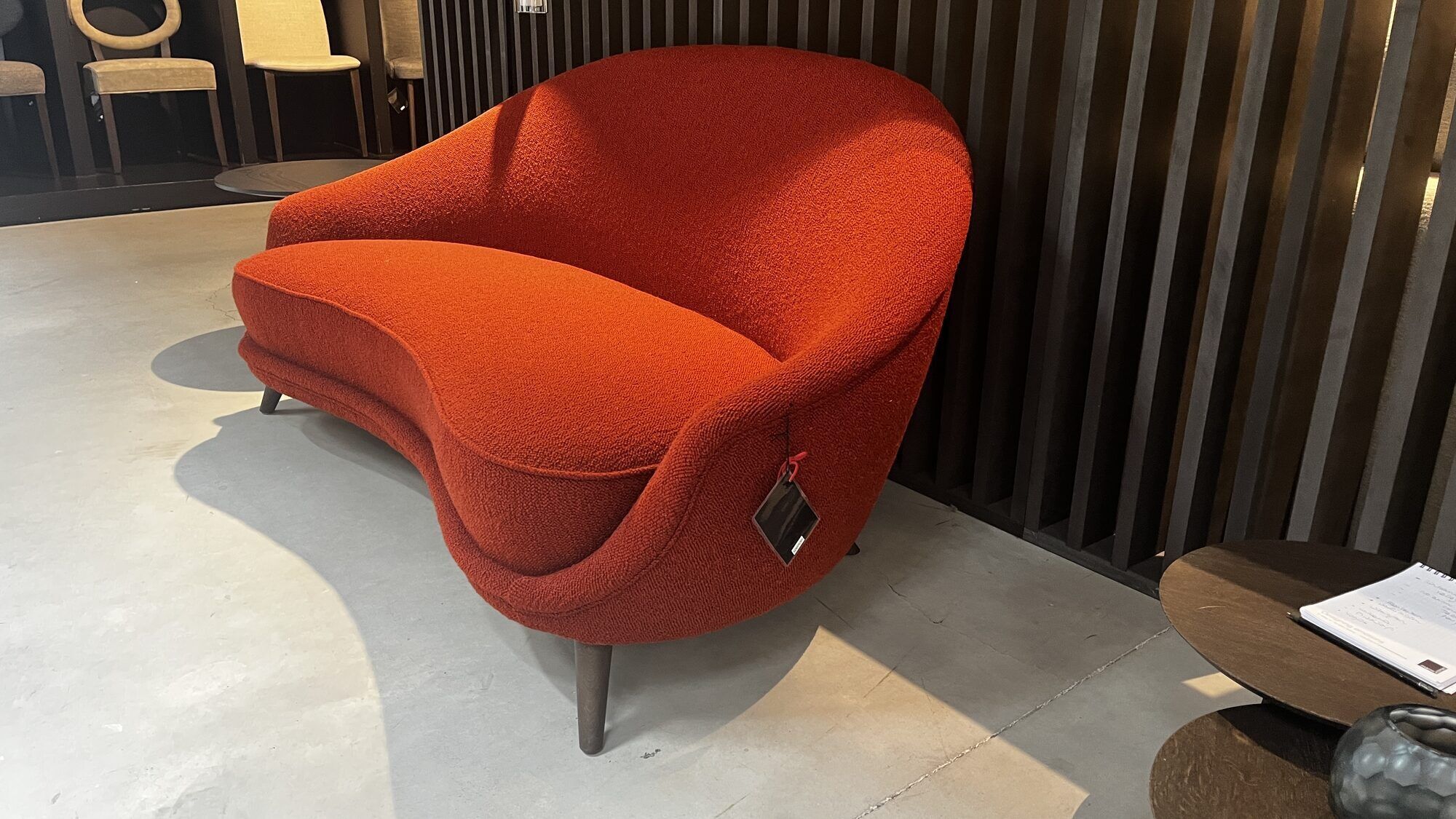 Two-seater sofa in red/orange boucle fabric.