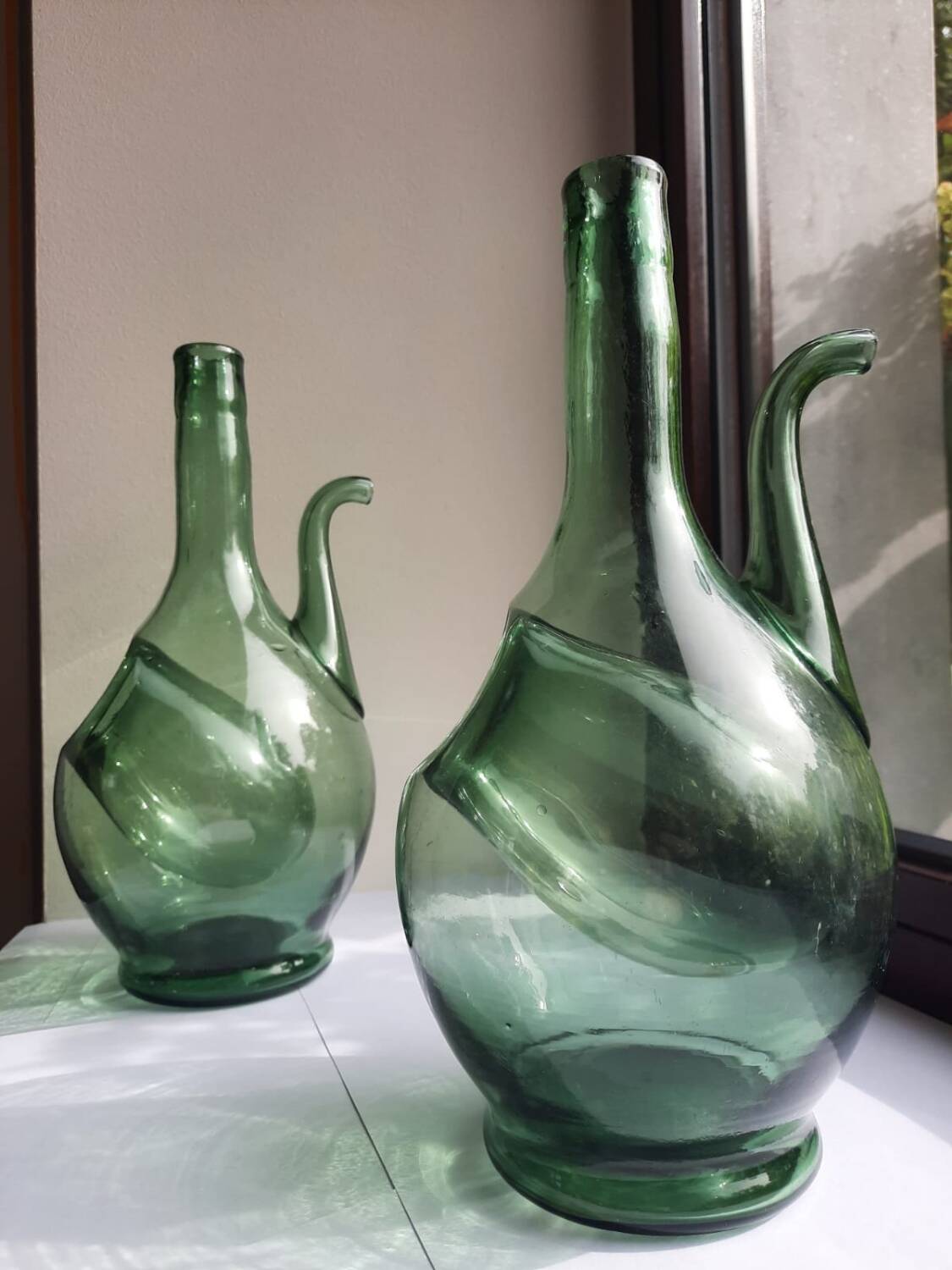 Pair of blown glass wine decanters in blue/green hues.