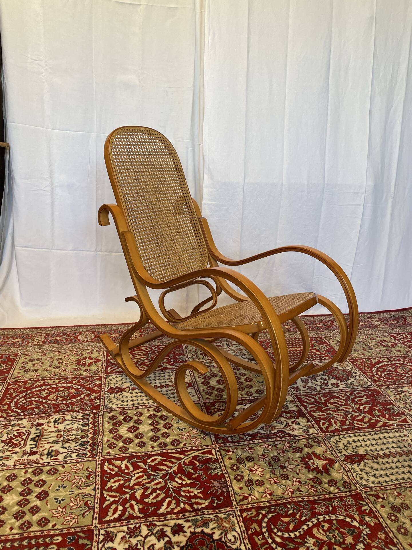 Antique rocking chair in curved wood and caning.