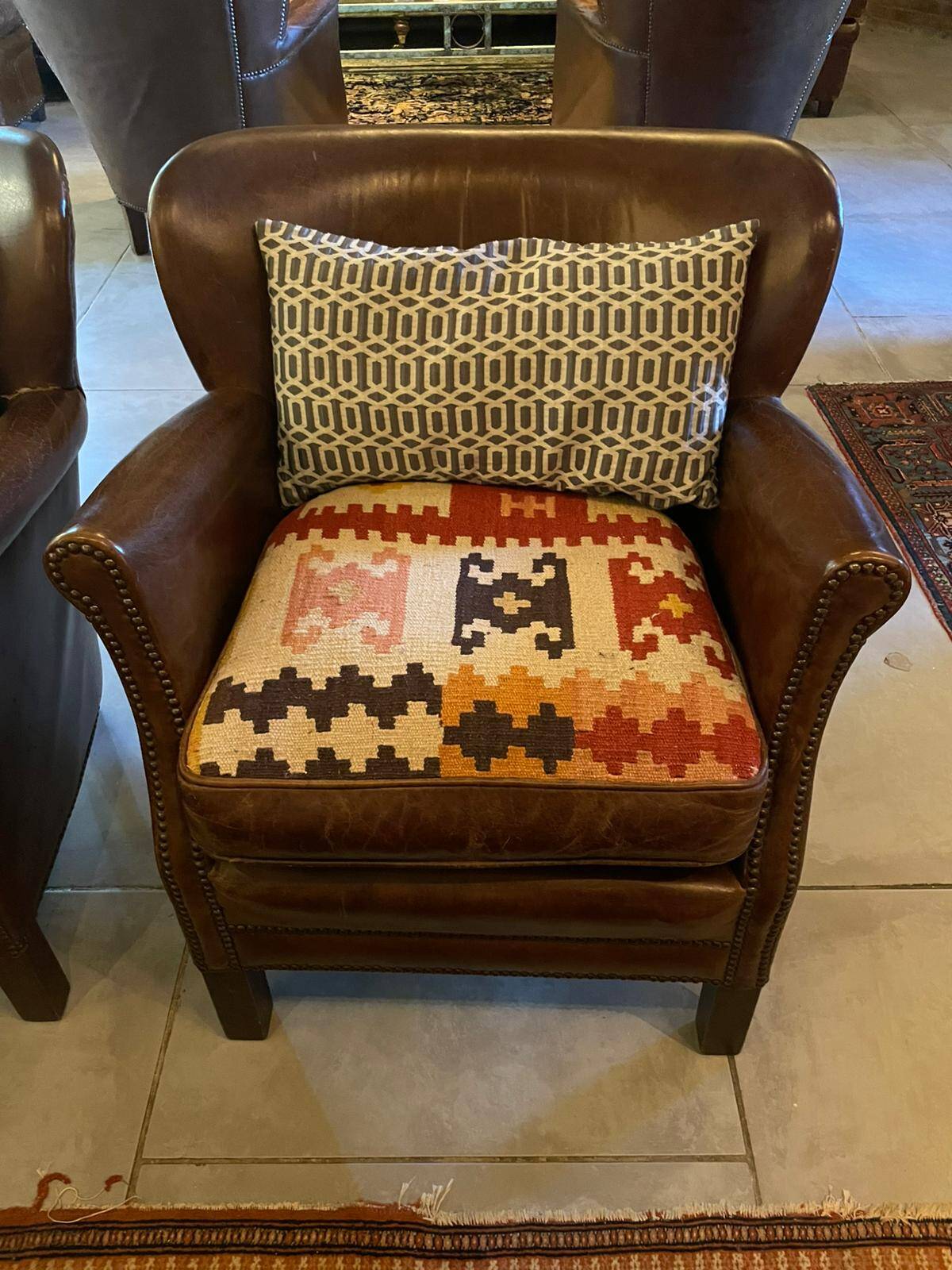 Brown cowhide armchair with a reversible seat cushion in KELIM.