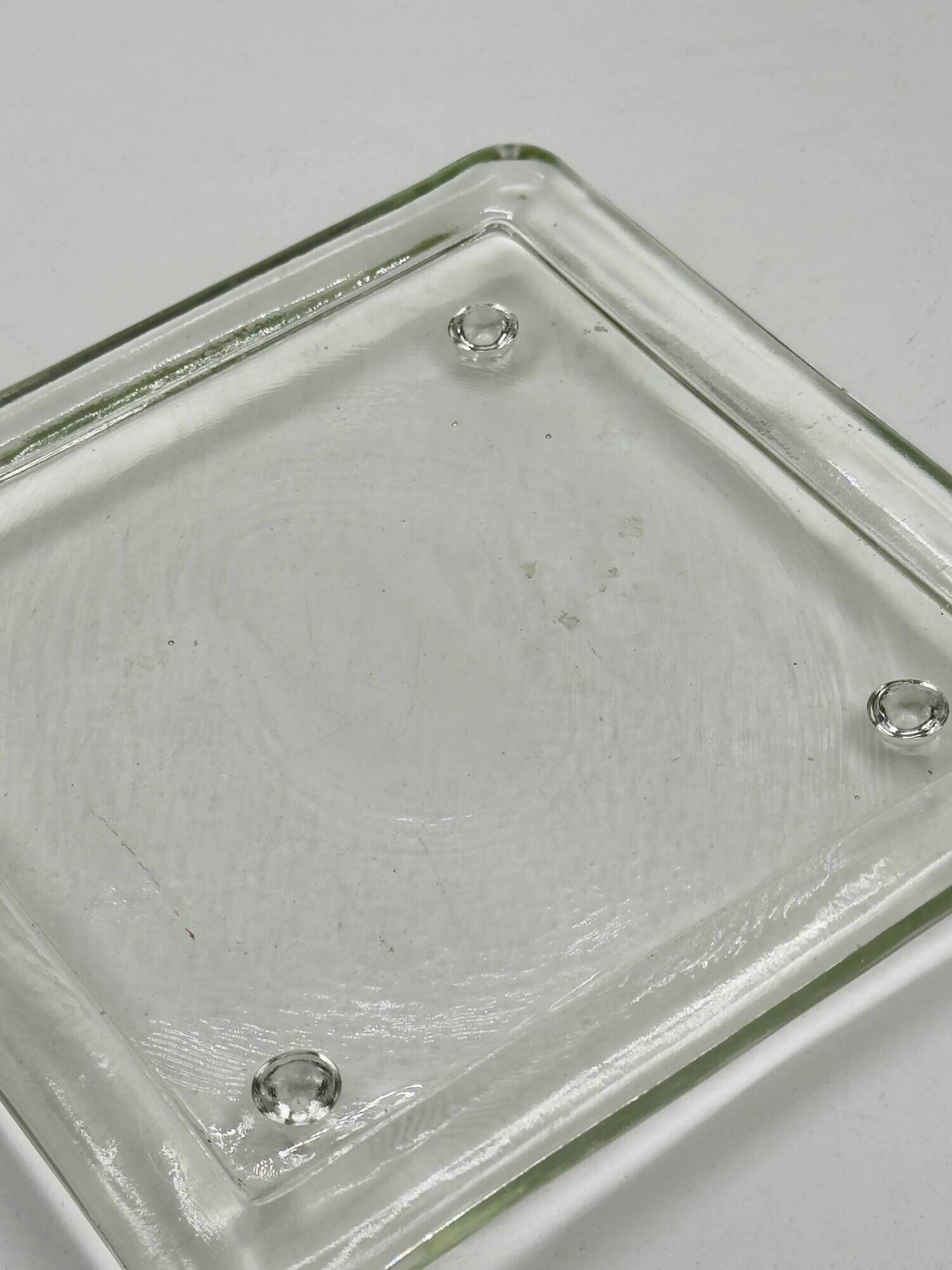 Vintage square serving tray in pale green tinted transparent glass with raised feet.