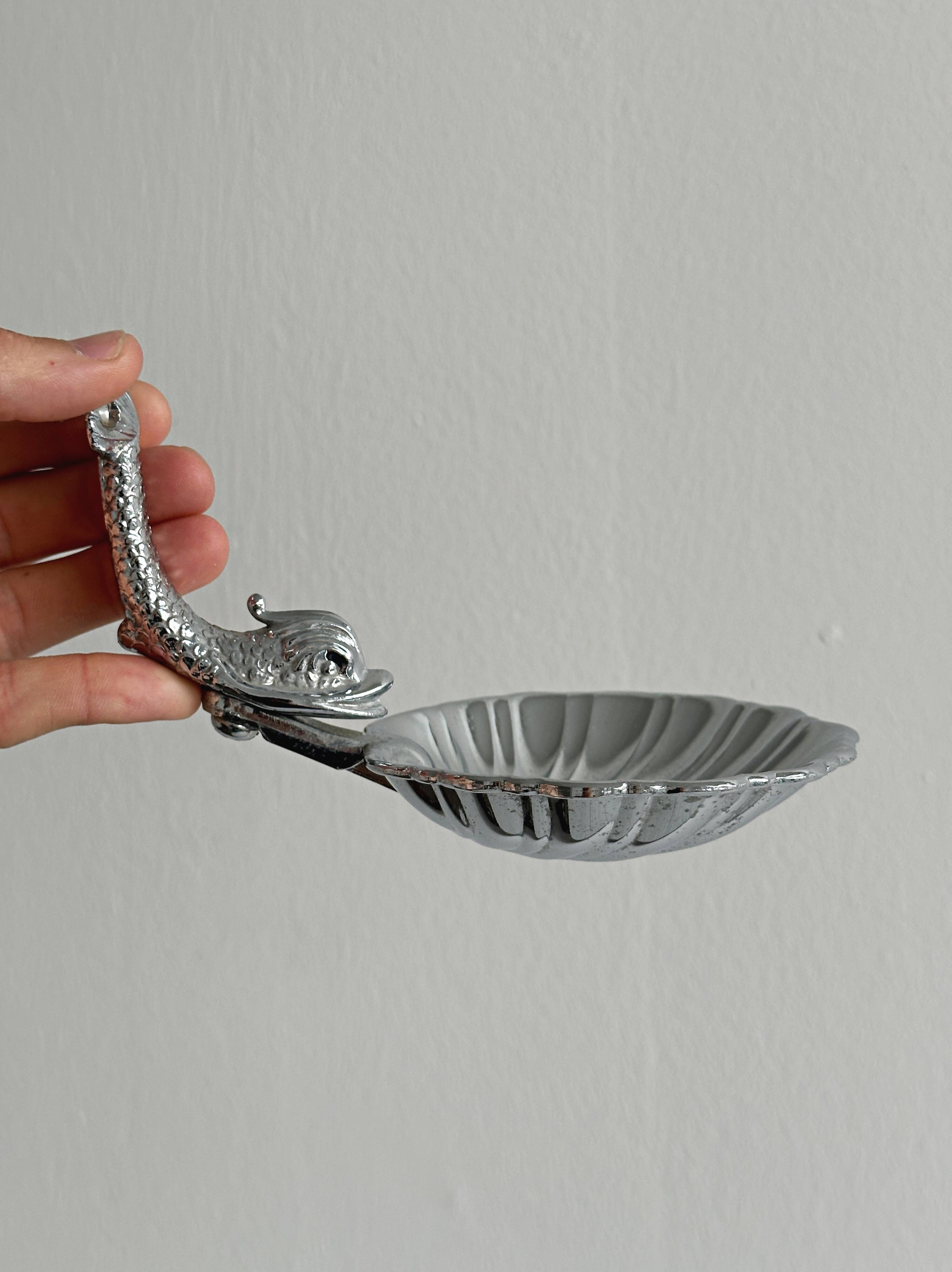 Soap dish, shell-shaped lightweight metal catchall.