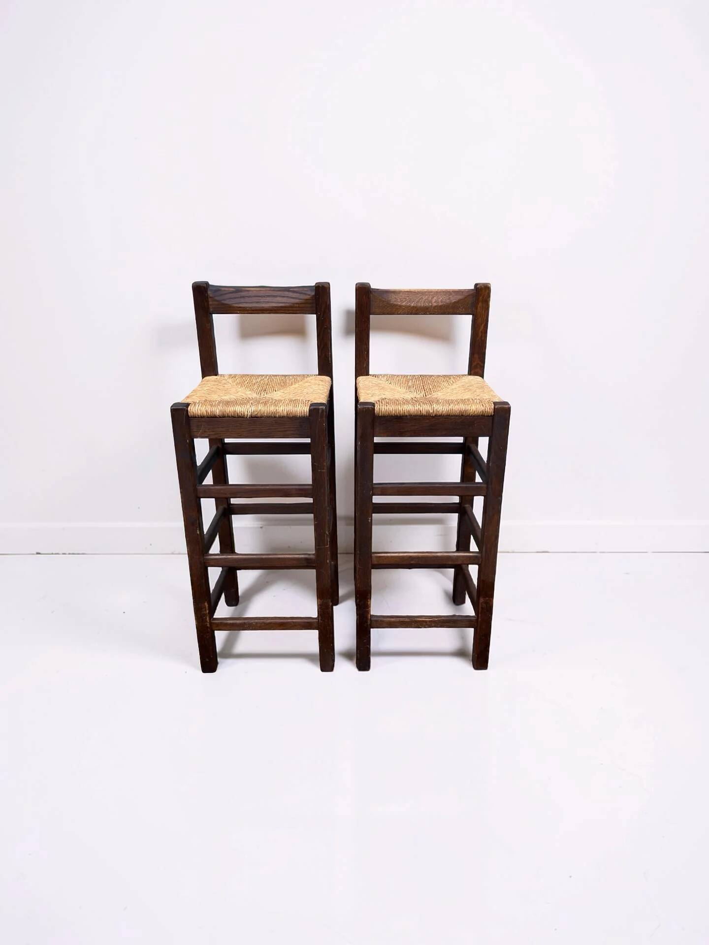 Set of 2 vintage wooden bar stools with woven straw seats.