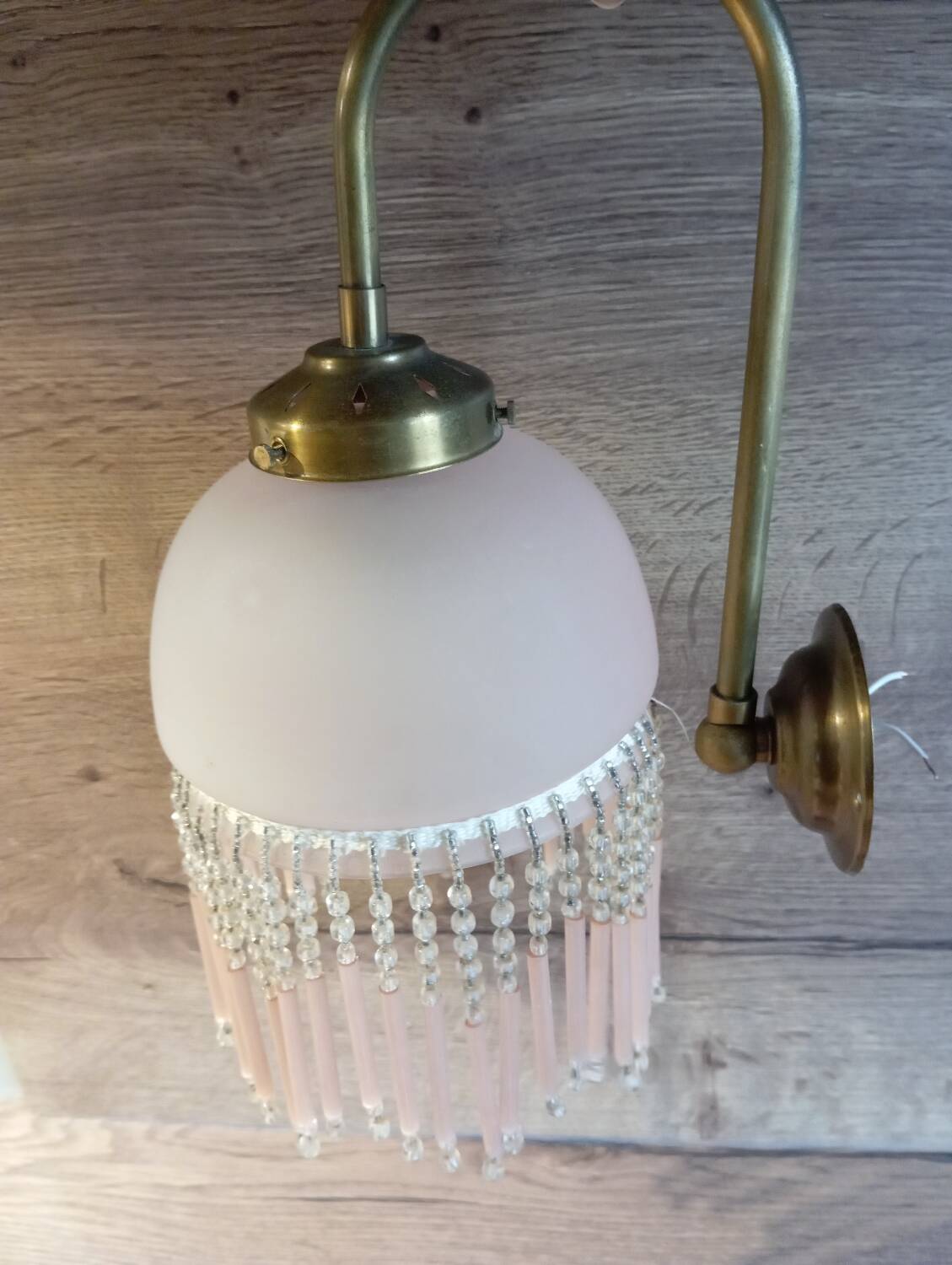 Brass swan neck wall lamp with pink glass globe and Charleston tassels