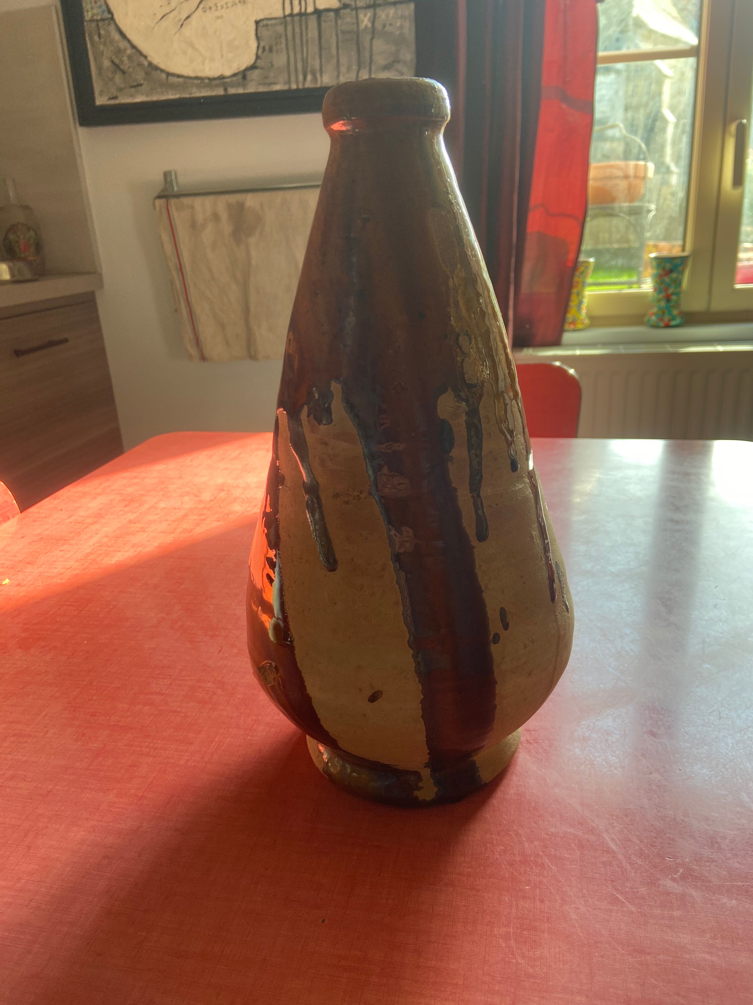 Large antique pottery bottle in glazed terracotta with drips.