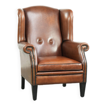 Sheepskin wingback armchair finished with black piping and a correct seat