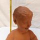 Terracotta bust of a smiling little boy.