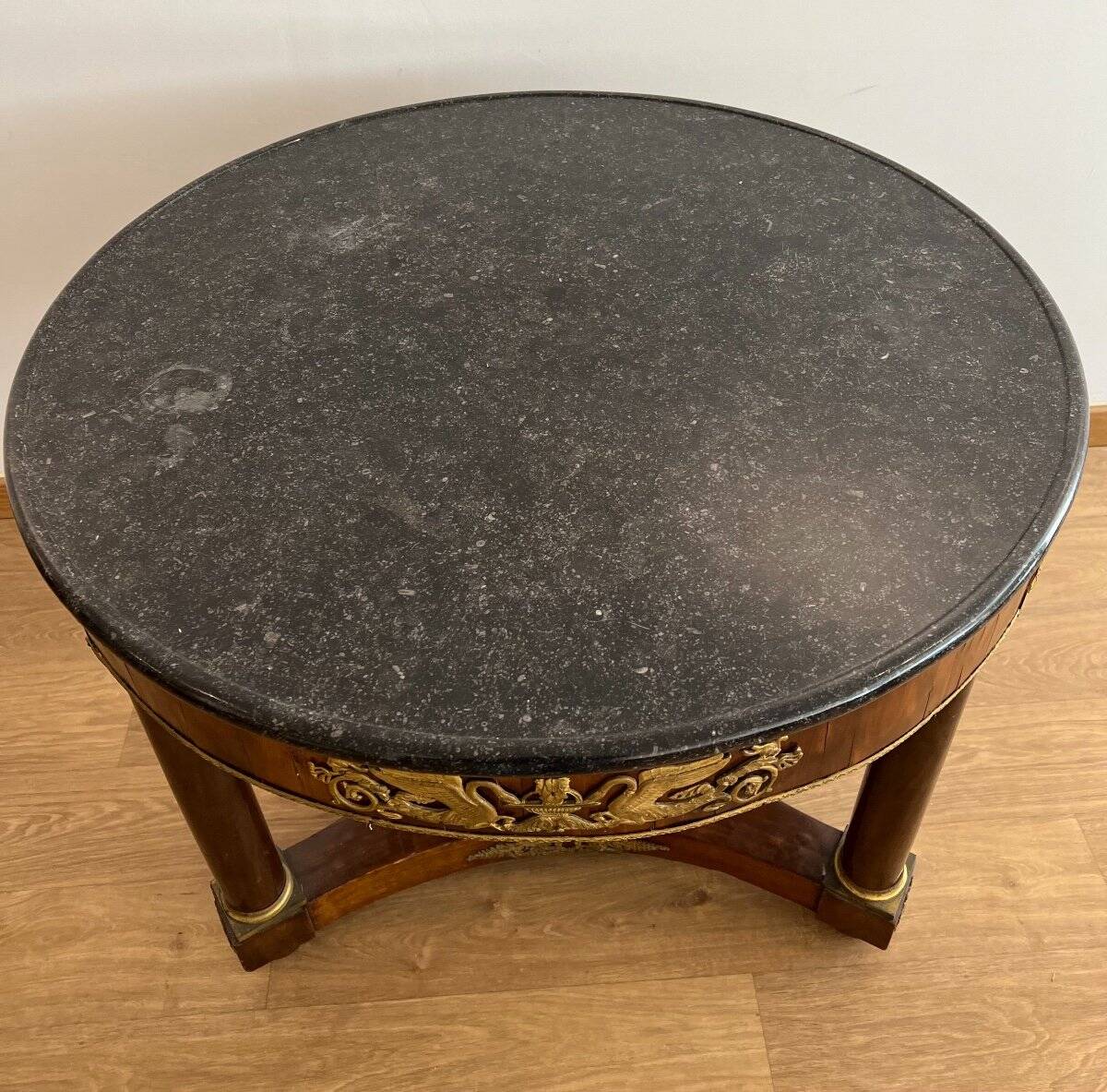 Empire gueridon in mahogany veneer adorned with chiselled and gilded bronze, topped with black marble with a groove.