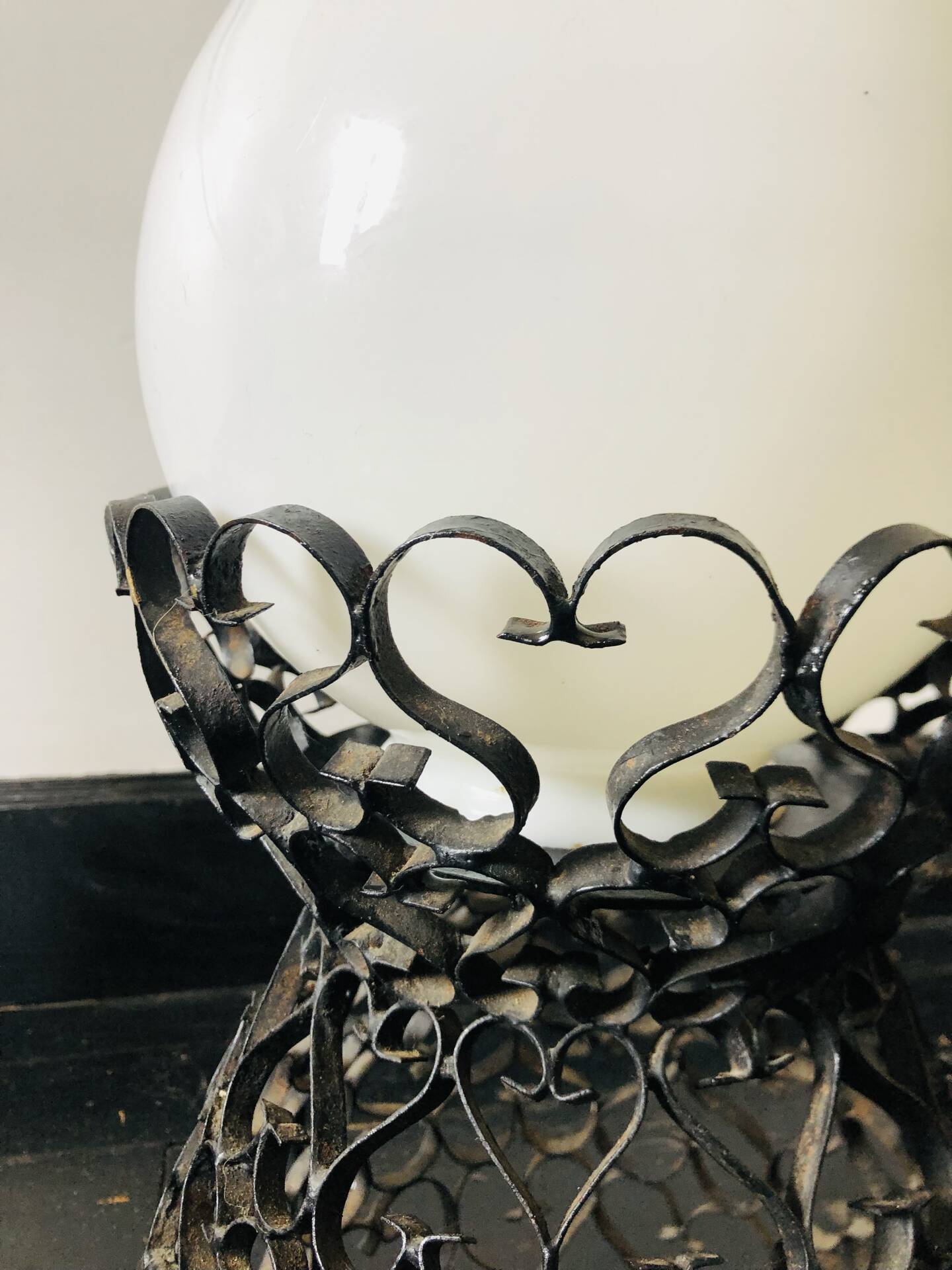 Handcrafted wrought iron lamp with a white opaline globe.