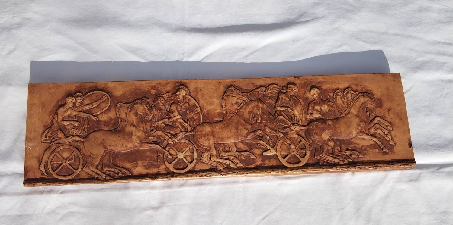 Bas-relief plaster scene of horses and a cart.