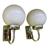 Pair of chrome metal wall lights with white glass globe.