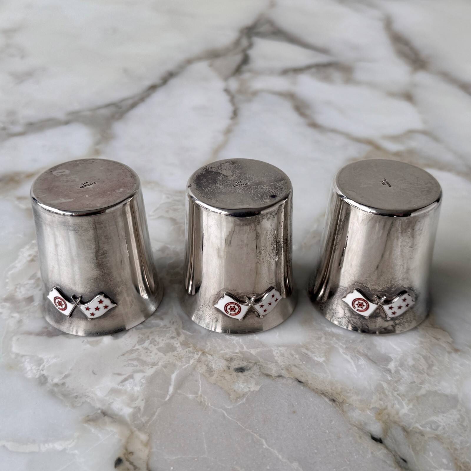 Set of 3 small silver 970 sterling cups with enamelled flags from the 20th century.